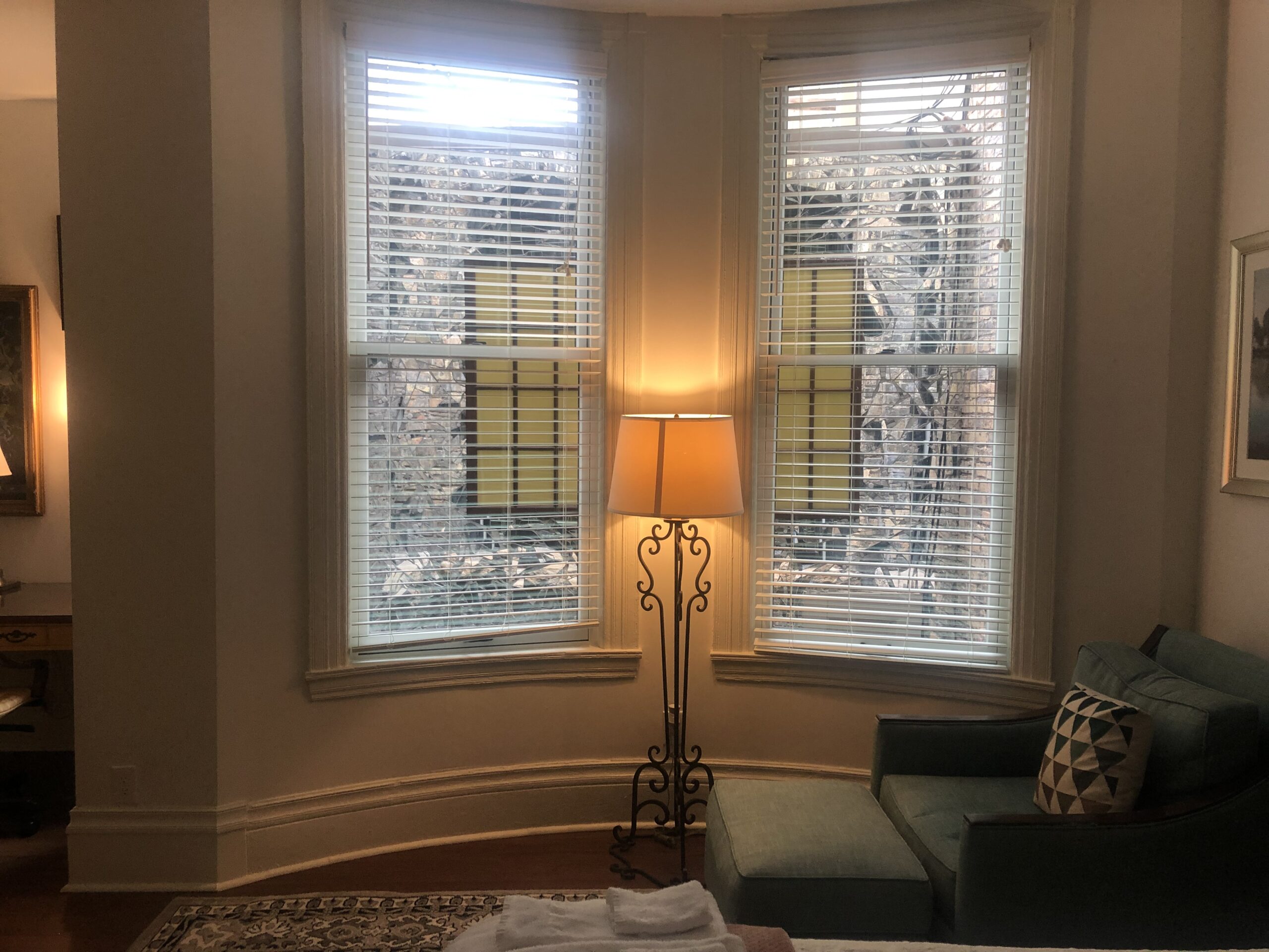 A bay window with a reading lamp and sofa inside a furnished studio at Oakland's on 9th, the 1889 brownstone extended-stay building in downtown Minneapolis