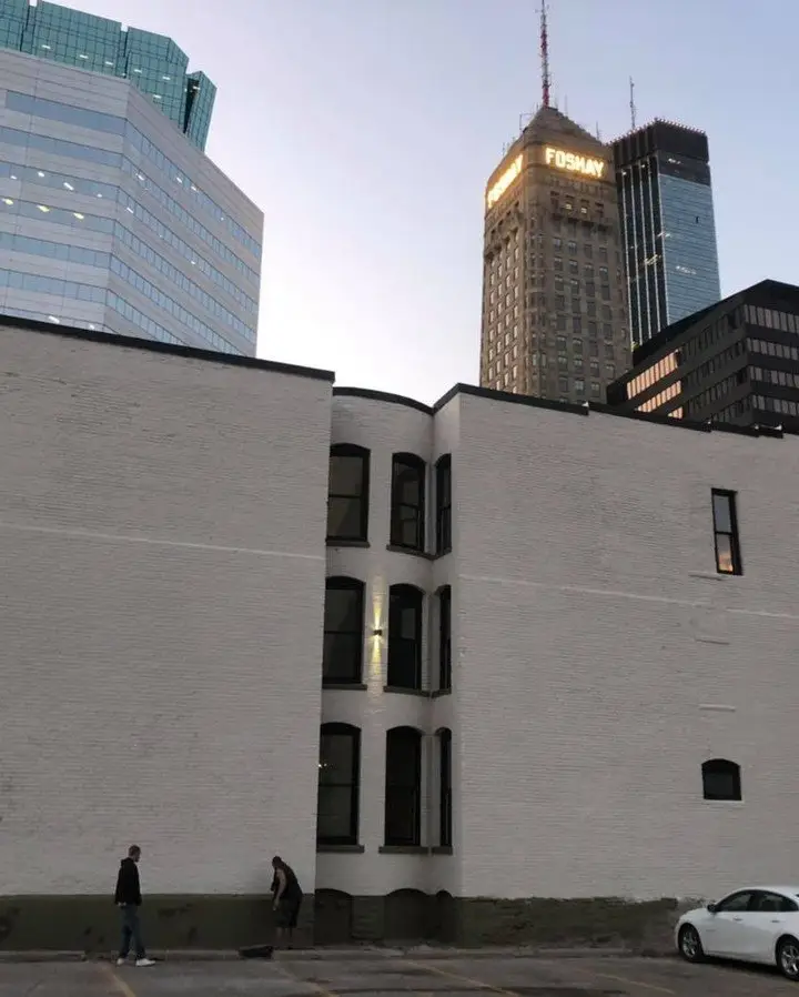 Oaklands on 9th brownstone at dusk in downtown Minneapolis with the lit Foshay Tower glowing behind it.
