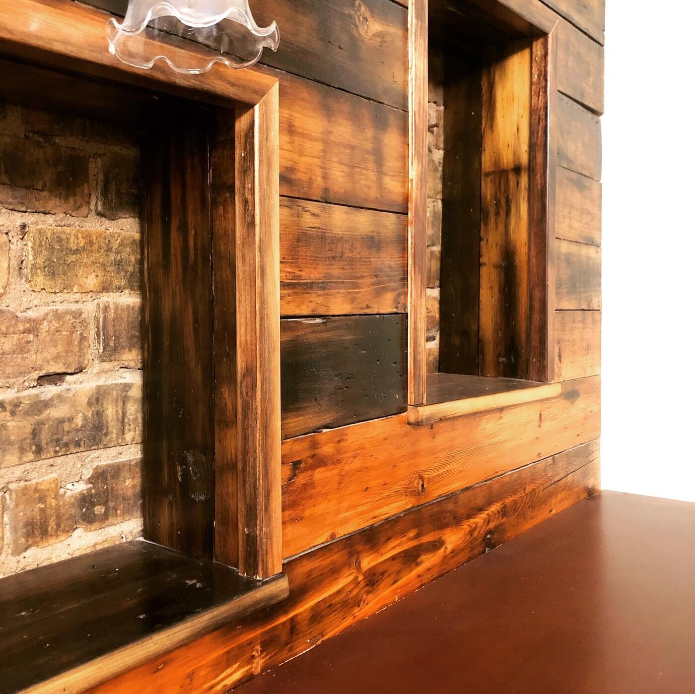 Reclaimed-wood storage cubbies framing exposed original 1889 brick inside a restored furnished studio at Oaklands on 9th in downtown Minneapolis.