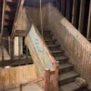 The Oaklands on 9th grand staircase mid-restoration, stripped to bare weathered wood after three winters exposed to the open sky.