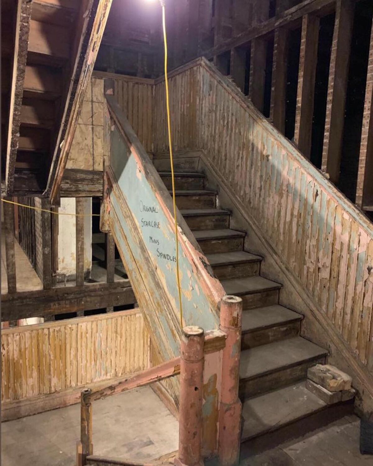 The Oaklands on 9th grand staircase mid-restoration, stripped to bare weathered wood after three winters exposed to the open sky.