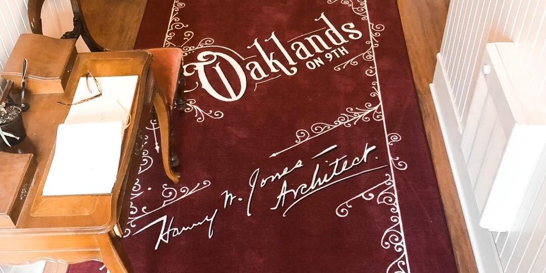Deep red entry runner at Oaklands on 9th reading 215 South 9th Street with architect Harry W. Jones's signature woven along the bottom.