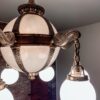 A restored antique brass and alabaster globe light fixture glowing in the exposed-brick stairwell at Oaklands on 9th in downtown Minneapolis.