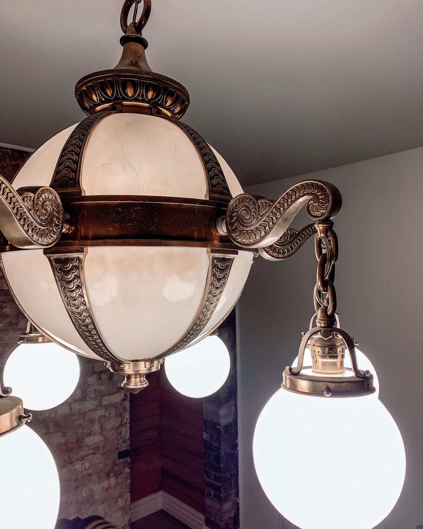 Restored antique brass and opal glass light fixture hanging at Oaklands on 9th, one of the unique restored fixtures in the building