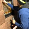 Craftsman restoring an original stained glass window set in the brownstone facade of Oaklands on 9th in downtown Minneapolis