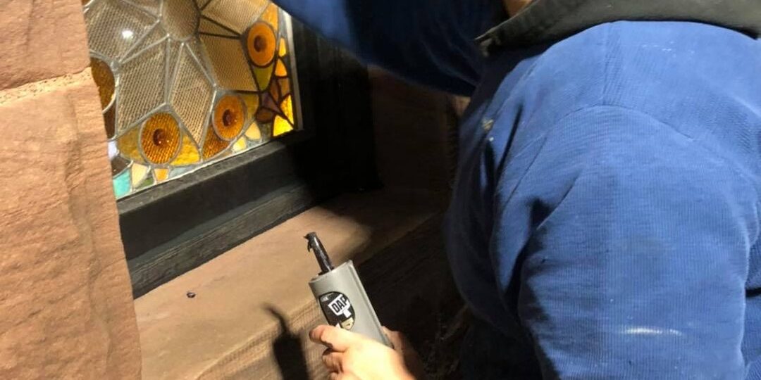 Craftsman restoring an original stained glass window set in the brownstone facade of Oaklands on 9th in downtown Minneapolis